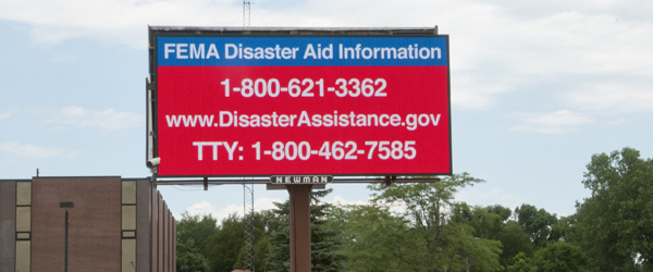 Vista de un cartel grande de FEMA que incluye el sitio web y los números de teléfono.